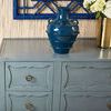 Close-up of tabletop on Sara Cabinet with blue vase and flowers against textured wall backdrop