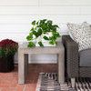 Partial rug under a gray woven sofa and concrete side table on brick floor in a porch setting