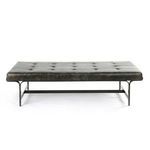 Full frame view showing tufted leather top, flat iron legs, and bench-style proportions