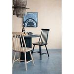 Side view of Sandhaven table paired with black and natural wooden spindle-back dining chairs in minimalist room