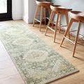 Rosette teal and ivory rug as a runner under wooden bar stools on light hardwood floor