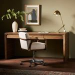 Styled view of Henry Desk with armchair, lamp, decorative vase, and artwork on muted green wall