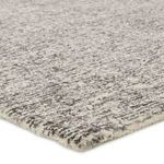 Close-up of rug corner showing soft, dense wool pile and tweed pattern in gray and cream