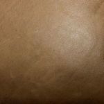 Side profile of warm brown leather recliner with extended footrest and angled back