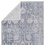 top corner of rug folded back to reveal backing and front blue-gray ornate design