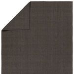 Revealed back of rug with folded corner showing consistent dark gray textured weave patterns