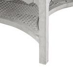 Close-up on corner leg and woven cane texture on lower shelf of white lacquered side table