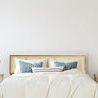 Styled queen bed in bedroom setting with neutral bedding, pillows, side tables, and lamps