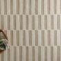 Close-up of rug showing alternating vertical linear stripes and hand-tufted wool texture with a wooden tray