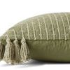 Side profile showing soft cotton back and thick tassels on the green embroidered pillow