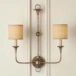Wall sconce installed with fabric drum shades diffusing warm light on a paneled light wall