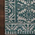 Close-up corner of teal and dove rug showing detailed woven geometric border and pattern