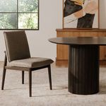 Charlie dining chair placed in a sunlit dining room beside round black dining table and wooden buffet
