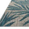 Close-up angled view showing woven texture and edge binding of grey and aqua tropical leaf rug
