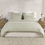 Full bed dressed with duvet and matching shams in solid sage color in a neutral bedroom