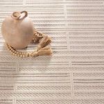 Decorative sphere and wooden bead garland on rug demonstrating texture and scale
