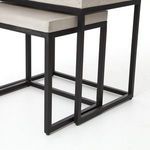 Detailed shot of matte black metal frame joints and concrete surface edges on nesting tables