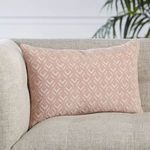 Lumbar pillow styled on light beige fabric sofa with green plant in background