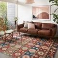 Zion Fiesta rug styled in modern living room with leather sofa, wood chair, and wall art