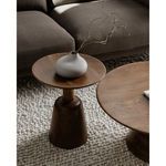 Side view of Nels end table with matte white vase and branches next to the coffee table on chunky rug