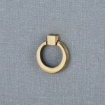 Close-up of antique brass circular ring drawer pull mounted on blue-gray linen textured drawer front