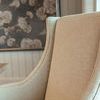 Close-up on chair back and angled arms showing fine beige upholstery texture