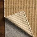Rug corner lifted to reveal underside pattern and a gray rug pad underneath on wood floor