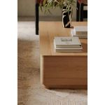 Close-up on the rounded corner edge and wood texture of Round Off Coffee Table with stacked books and vase