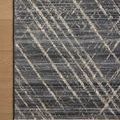 Corner of Wade Midnight Beige Rug on wood floor highlighting fringed edges and pattern overlapping floor
