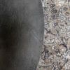 Close-up of the table’s textured round surface placed on a patterned area rug.