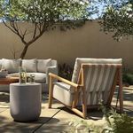Chair positioned outdoors viewed from behind, with strap-backed frame and garden backdrop