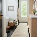 Long runner edition of Chris Natural Sage Rug in a bright bathroom with wood cabinetry and black tile floor