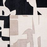 Overlap comparison of taupe cream rug placed over a black and cream version of the rug
