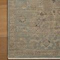 Close-up of Briar Sky Grove rug corner showing subtle floral motifs and distressed vintage look on wooden floor