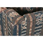 Rounded front wooden leg with brass caster wheel detail beneath patterned sofa fabric