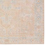 Close-up on the rug’s intricate corner design with beige and blue tribal motifs