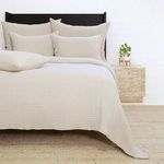 Queen-sized Vancouver Coverlet in natural cotton with subtle quilted texture on bed with matching pillows