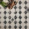 Close-up of rug’s textured diamond pattern with small decorative beads and greenery accent.