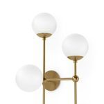 Close-up angled view of top three matte white glass globes and connecting brass rods of Armstrong 4 R Sconce