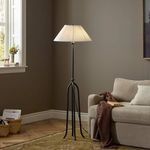 Rydell floor lamp lit in a living room next to beige sofa and brown throw blanket