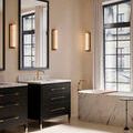 Lit Blaine sconce mounted on wall, showing soft warm light from milky glass and brass