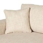 Square beige throw pillow resting against back cushion on Peyton Sofa seat