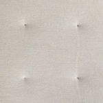 Close-up of beige fabric cushion showing button tuft detail and linen-like texture