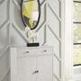 Oval mirror hanging on geometric-patterned light gray wall over white cabinet with horse sculpture