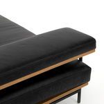 Top angled close-up showing leather cushion edges and oak frame detail beneath armrest pillow
