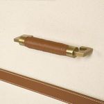 Detail of brushed brass and leather drawer pull with artisanal stitched leather wrap