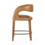 Side profile of Hawkins stool highlighting rounded backrest and leather upholstery