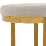 Close-up of thick antique gold leaf finish on iron base under the upholstered white seat