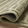 Bradley Sage rug partially rolled to reveal thickness and wool texture