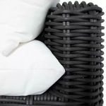 Close-up detail of woven rattan armrest with white cushion corners